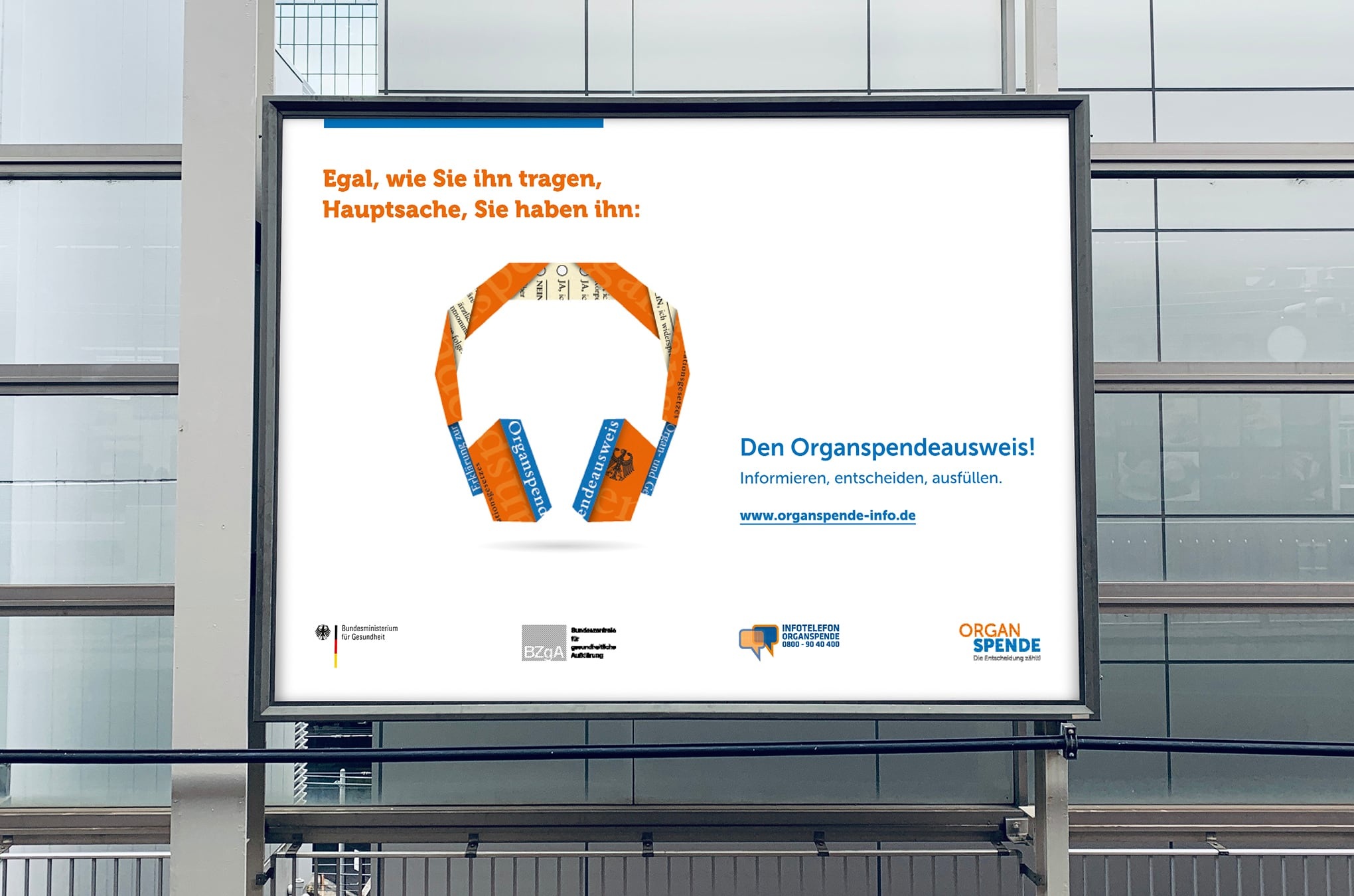 Plakat der Kampagne zur Organspende. Links steht &quot;Egal, wie Sie ihn tragen. Hauptsache, Sie haben ihn.&quot; Darunter ist ein Organspendeausweis abgebildet, der zu einem Kopfh&ouml;rer gefaltet wurde.