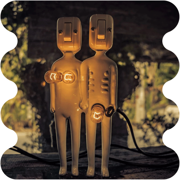 Zwei kleine Figuren in Form von Menschen, die mit Gl&uuml;hbirnen und Lichtschaltern versehen sind, stehen nebeneinander.